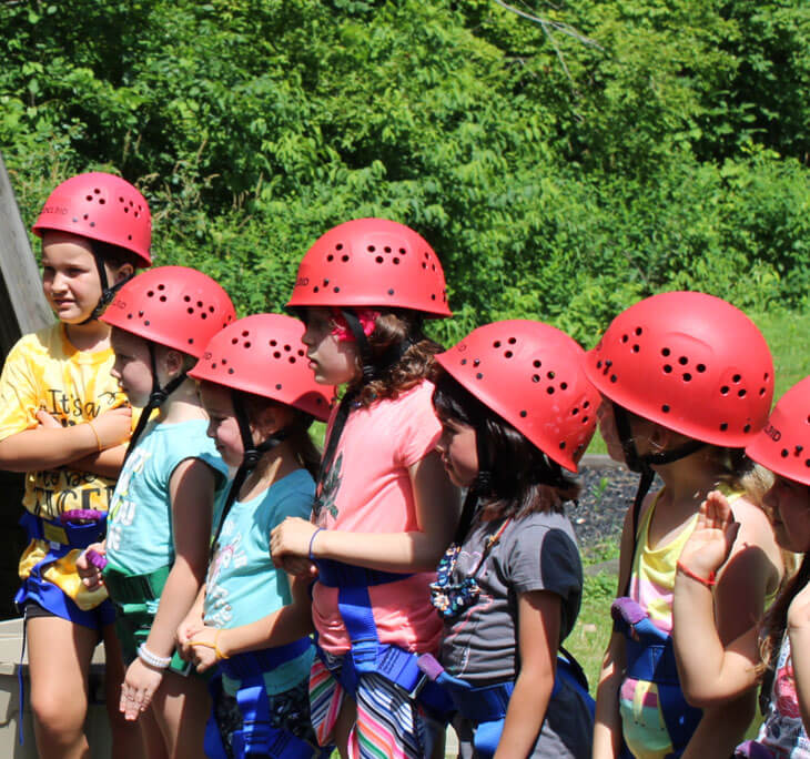 Children lined up with hard hats to go climbing.